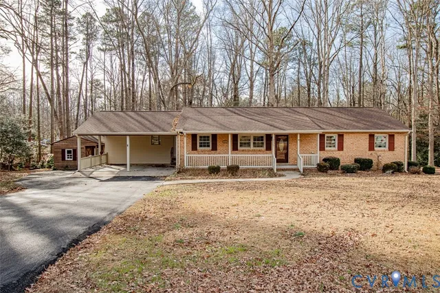 a front view of a house with a dirt yard and a large tree