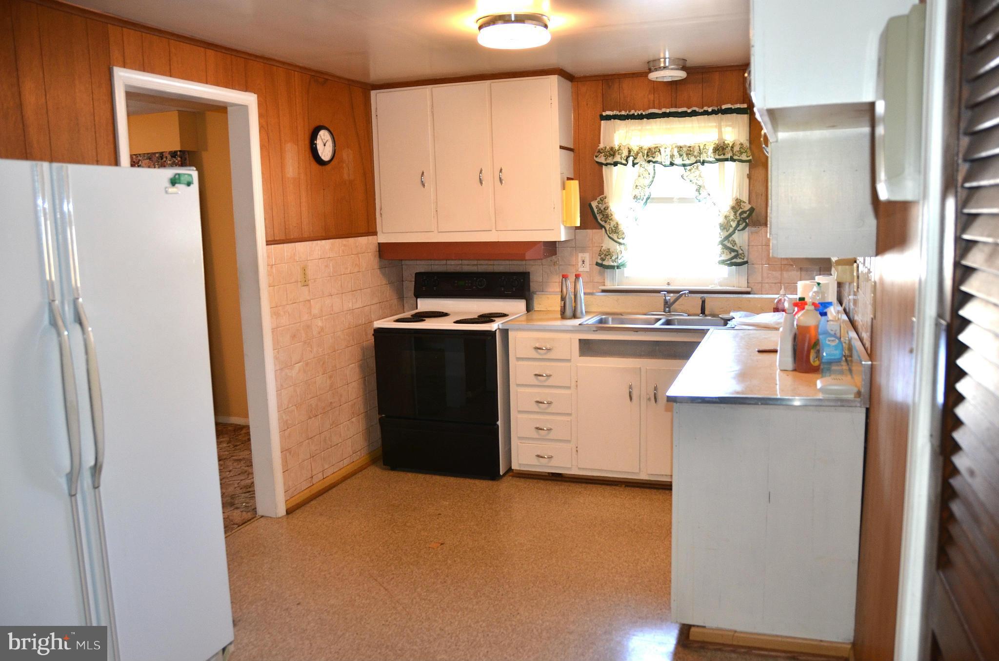 1637 Hilltop Road Edgewater, MD 21037 - Photo 6 of 20 a kitchen with a refrigerator a stove a washer dryer and white cabinets