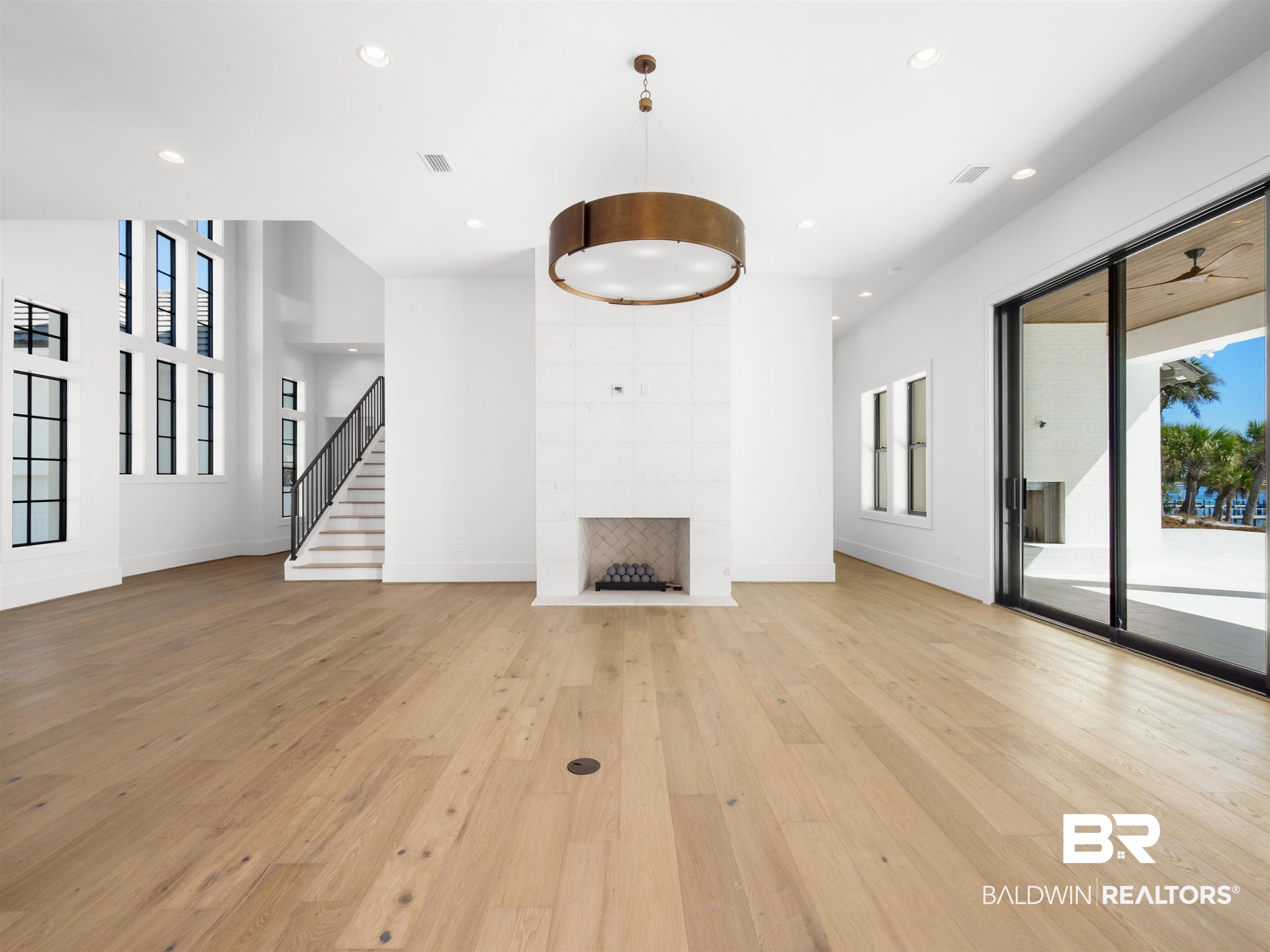31292 River Road Orange Beach, AL 36561 - Photo 3 of 48 Unfurnished living room featuring recessed lighting, stairway, a tiled fireplace, light wood-type flooring, and baseboards