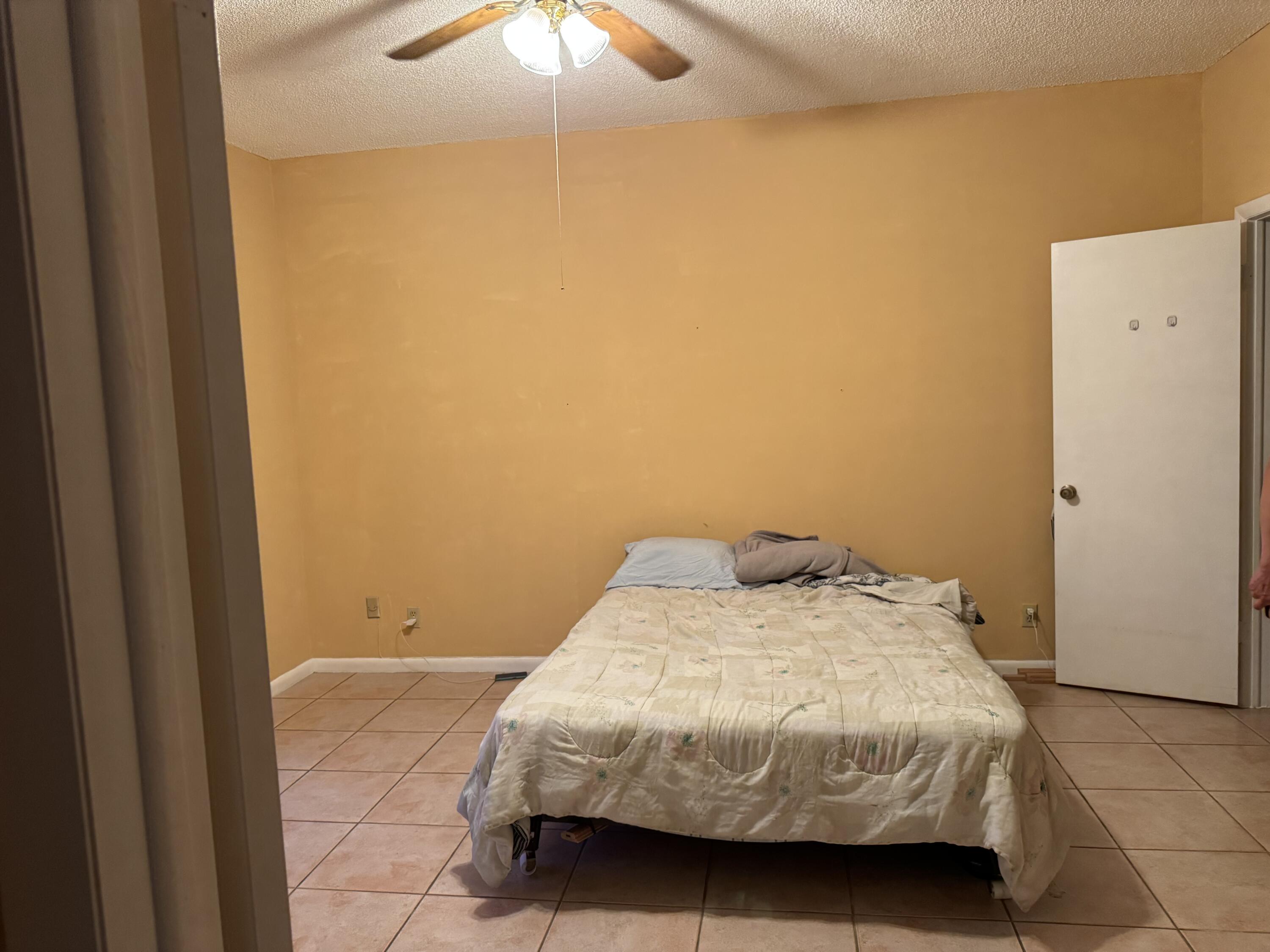 4101 Waterview Circle, Unit 41A Palm Springs, FL 33461 - Photo 25 of 26 a bedroom with a bed and a chandelier