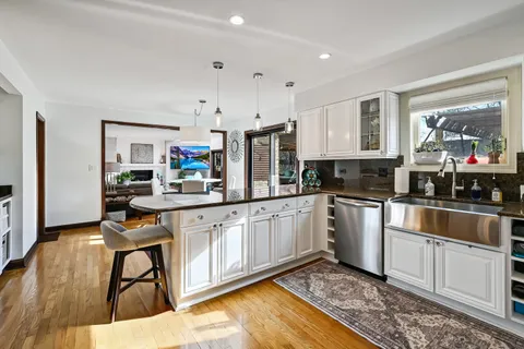 a kitchen with stainless steel appliances granite countertop a stove top oven a sink dishwasher and cabinets with wooden floor