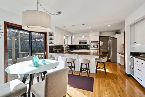 a kitchen with stainless steel appliances granite countertop a stove a refrigerator a kitchen island a dining table and chairs