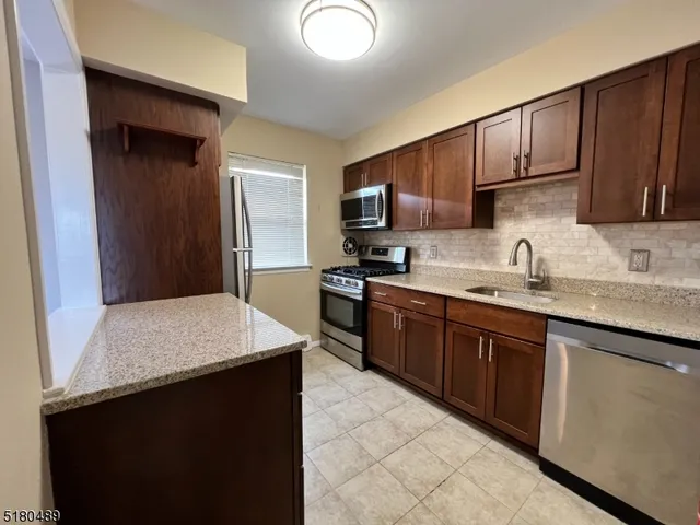 a kitchen with kitchen island granite countertop a sink dishwasher stove and cabinets