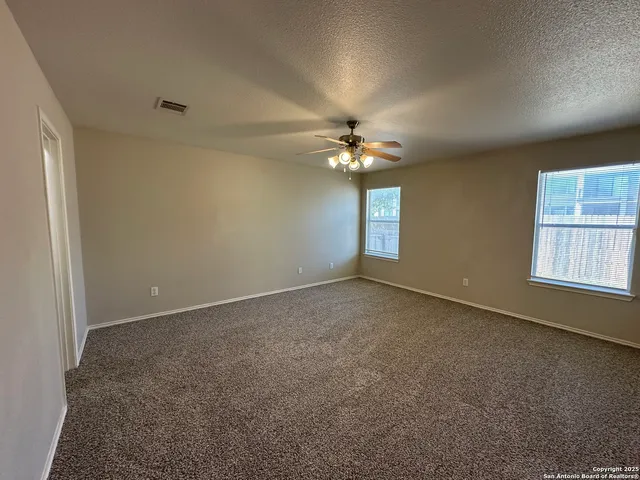 an empty room with a chandelier fan and windows