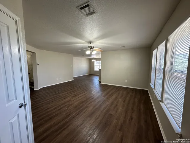 an empty room with wooden floor and a ceiling fan
