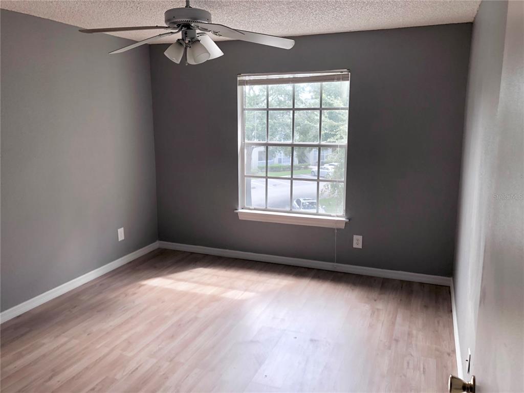 1037 South Hiawassee Road, Unit 2835 Orlando, FL 32835 - Photo 15 of 18 an empty room with wooden floor chandelier fan and windows
