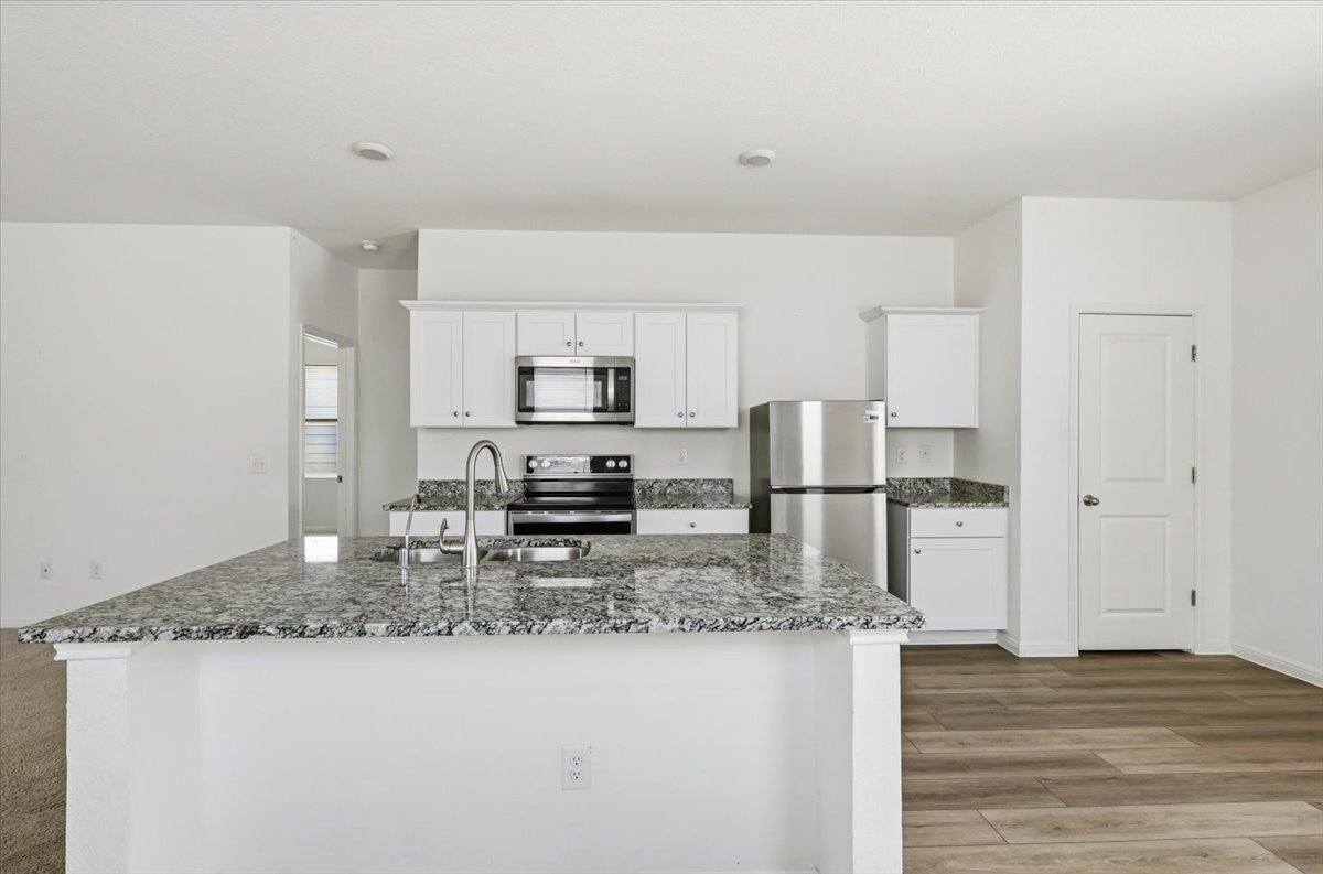 202 Peridot Pass Maxwell, TX 78656 - Photo 7 of 21 A chef's dream, this kitchen boasts an island with a breakfast bar, white cabinetry, and modern stainless steel appliances.