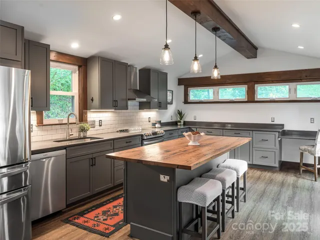 a kitchen with stainless steel appliances granite countertop a sink a stove a refrigerator and island with wooden floor