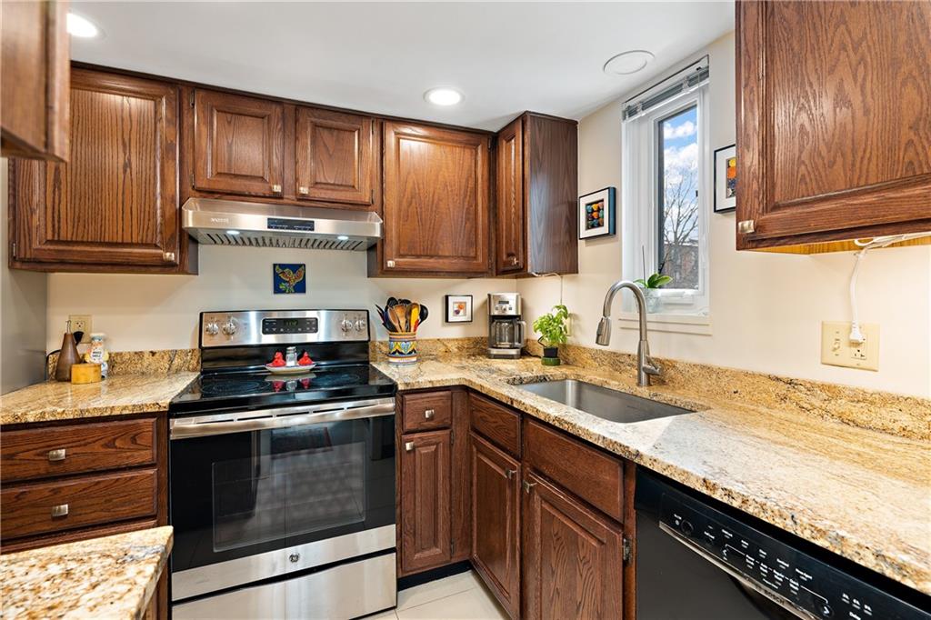 7 Foster Square Pittsburgh, PA 15212 - Photo 9 of 22 a kitchen with granite countertop wooden cabinets and a stove top oven