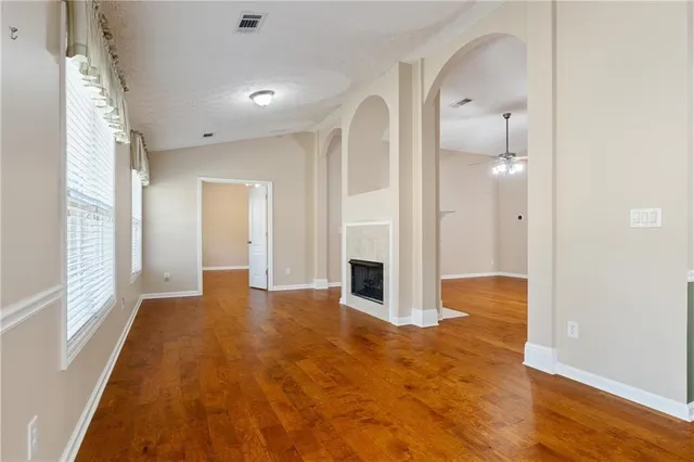 a view of a hallway with wooden floor and a bathroom