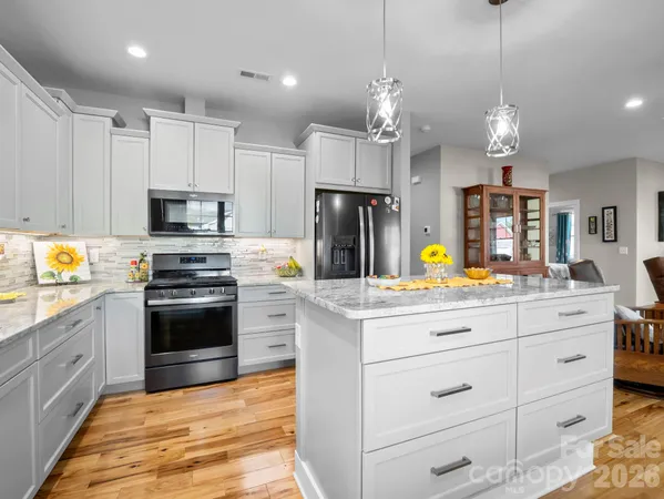 a kitchen with a refrigerator stove and white cabinets with wooden floor
