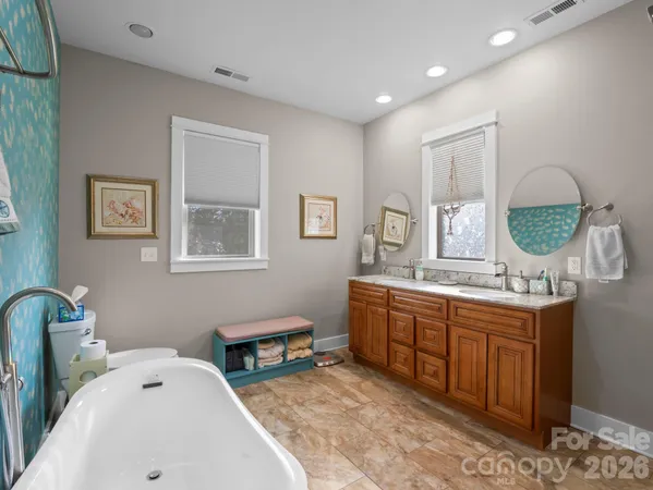a spacious bathroom with double vanity a mirror and a lamp