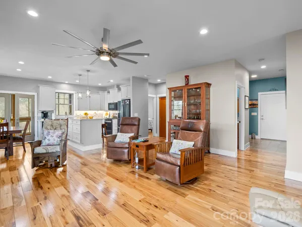 a living room with furniture and kitchen view with wooden floor