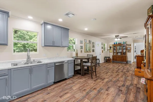 a kitchen with stainless steel appliances granite countertop a refrigerator a stove and a sink with wooden floor