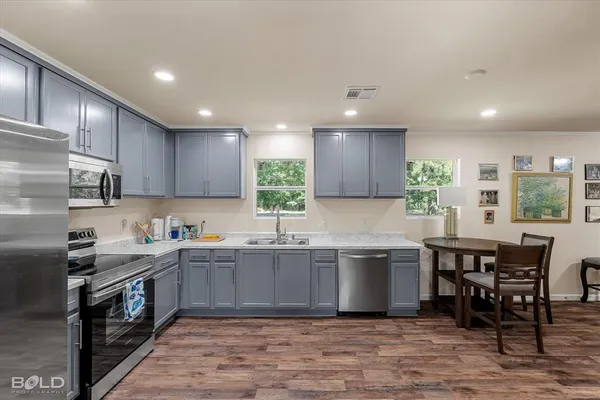 a kitchen with stainless steel appliances granite countertop a table chairs sink refrigerator and cabinets