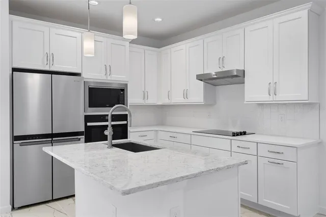 a kitchen with stainless steel appliances granite countertop a refrigerator a oven a sink and a refrigerator