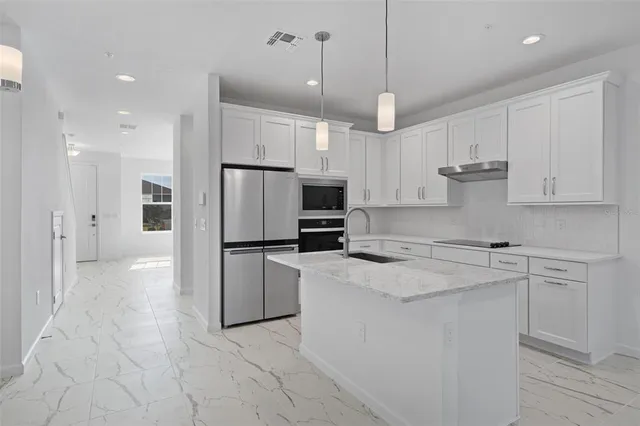 a kitchen with kitchen island a counter top space appliances and cabinets