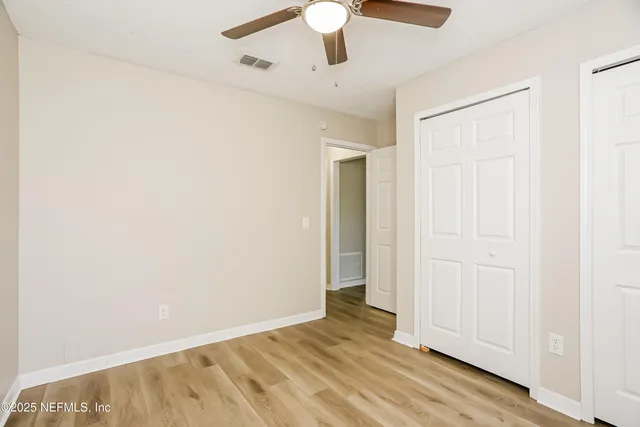 an empty room with wooden floor closet and windows