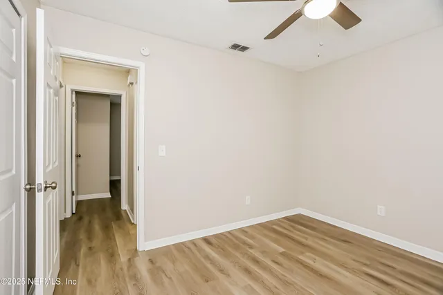an empty room with wooden floor and a ceiling fan
