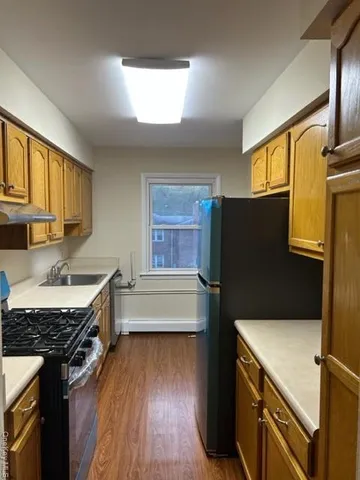 a kitchen with a refrigerator a sink and wooden floor