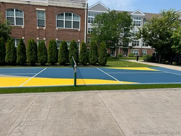 a view of a swimming pool with lawn chairs and large trees