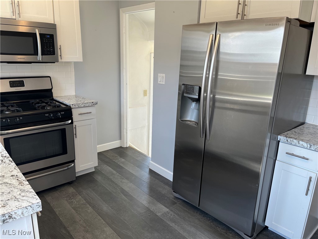 29946 Enid Road Wickliffe, OH 44092 - Photo 20 of 50 Kitchen with Vinyl/LVT flooring, appliances with stainless steel finishes, white cabinets, and decorative backsplash