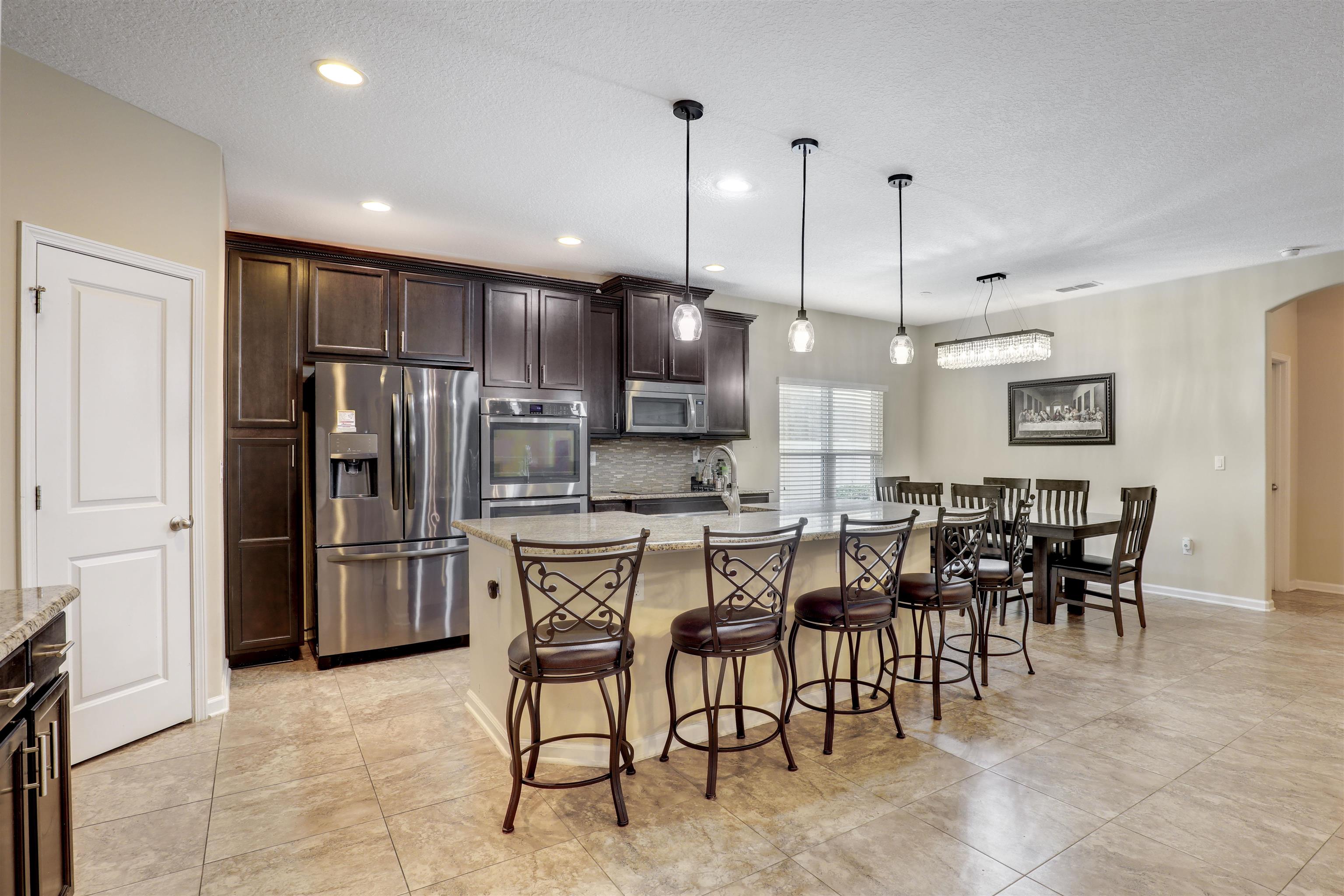 200 Ellsworth Circle St. Johns, FL 32259 - Photo 17 of 58 a kitchen with stainless steel appliances kitchen island granite countertop a refrigerator a stove a dining table and chairs
