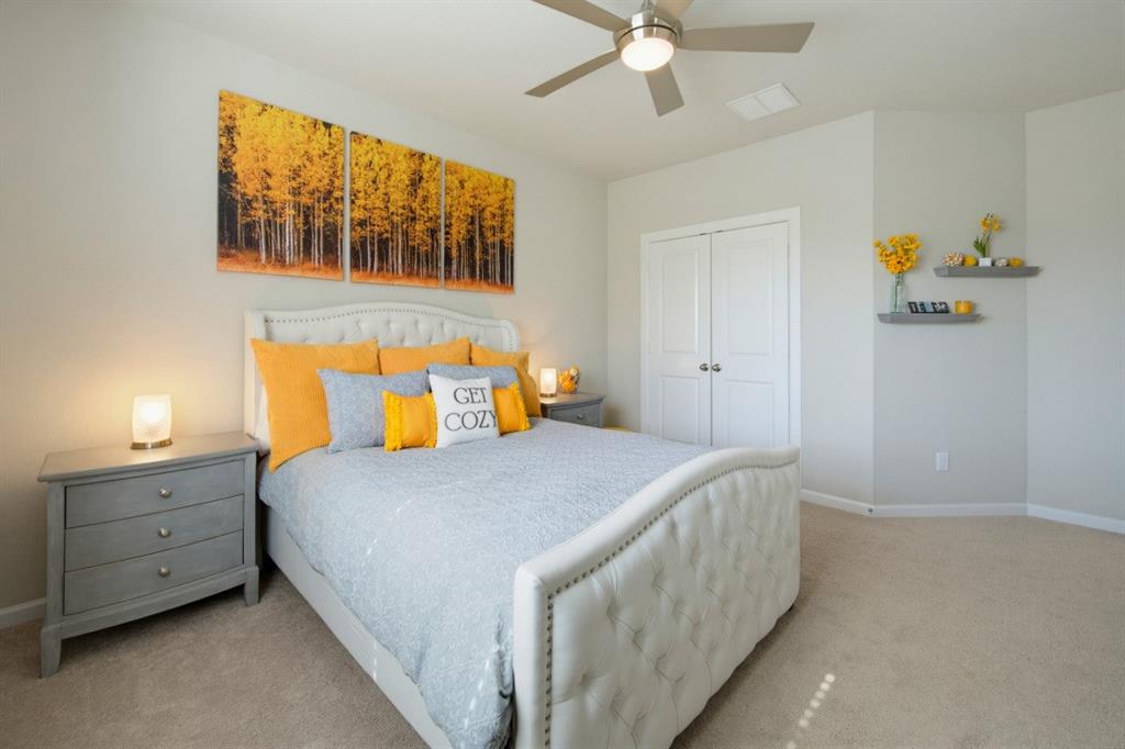 2721 Old Shire Path Road Prosper, TX 75078 - Photo 23 of 39 Carpeted bedroom featuring a ceiling fan with integrated lighting, double-door closet, and floating wall shelves