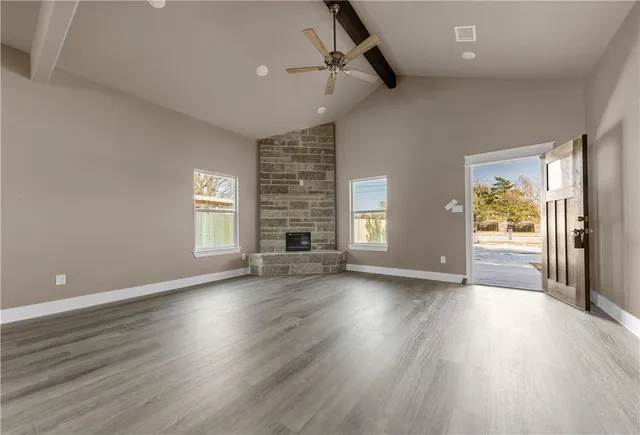 an empty room with wooden floor fireplace and windows