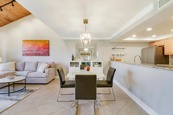 a dining room with furniture a chandelier and kitchen view