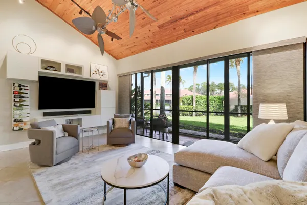 a living room with furniture a flat screen tv and a floor to ceiling window