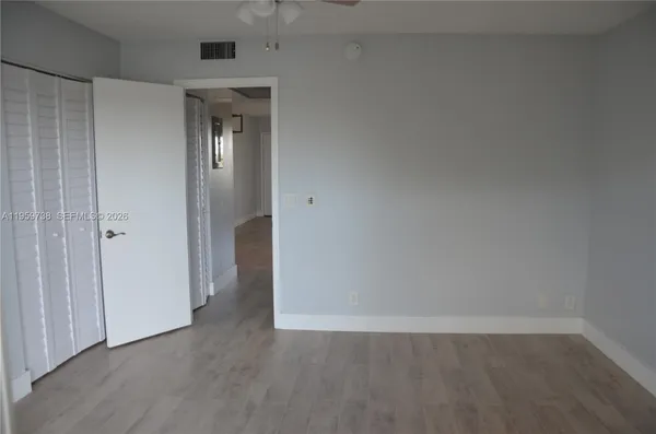 a view of an empty room with wooden floor and closet