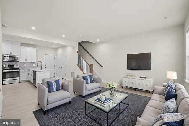 a living room with furniture a flat screen tv and kitchen view