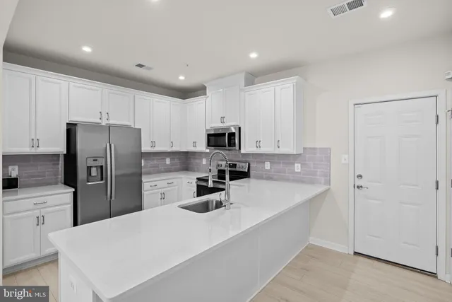 a kitchen with refrigerator a stove a sink and cabinets