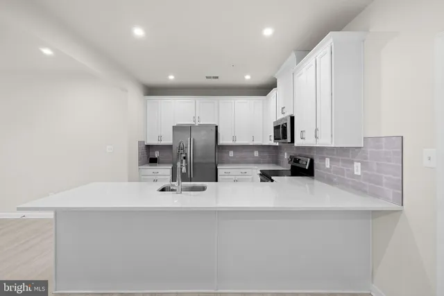 a kitchen with kitchen island a sink stainless steel appliances and cabinets
