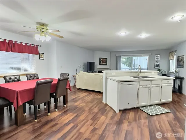 a room with kitchen island a sink dishwasher a dining table and chairs with wooden floor