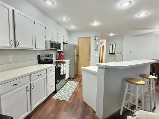 a kitchen with kitchen island a white counter top space cabinets and stainless steel appliances