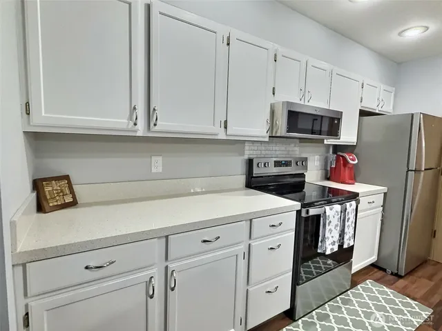 a kitchen with stainless steel appliances white cabinets and a refrigerator