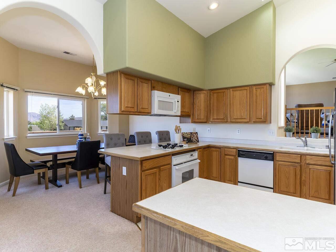 1090 Reese Way Reno, NV 89521 - Photo 16 of 33 a kitchen with a stove a sink a dining table and chairs