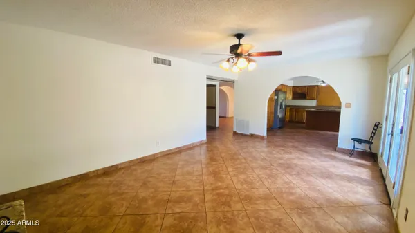 a view of a big room with wooden floor a chandelier fan and windows