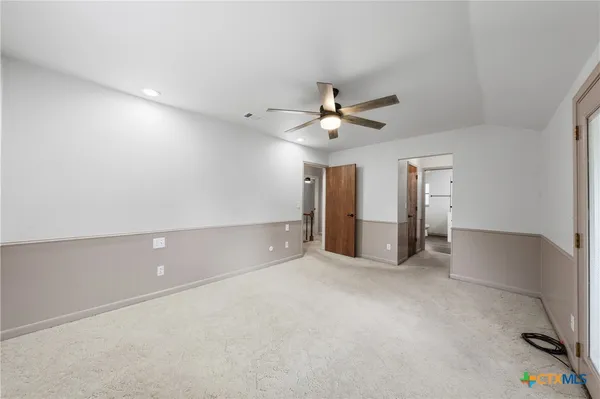 an empty room with windows and ceiling fan