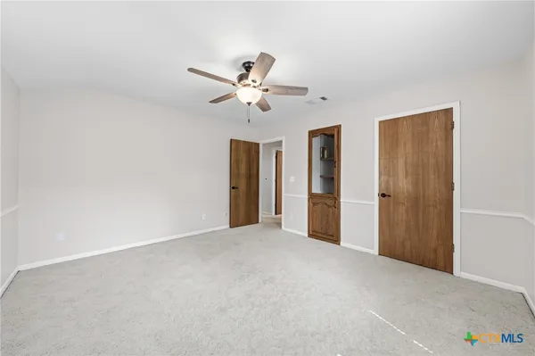 an empty room with ceiling fan and windows