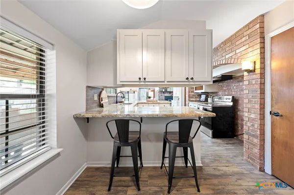 a kitchen with stainless steel appliances granite countertop a table chairs in it and wooden floors