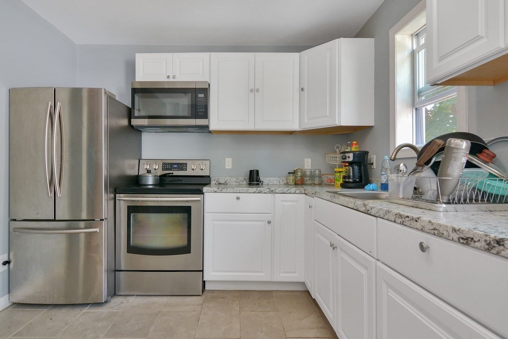 10 Holly Street Lawrence, MA 01841 - Photo 5 of 32 a kitchen with white cabinets and stainless steel appliances