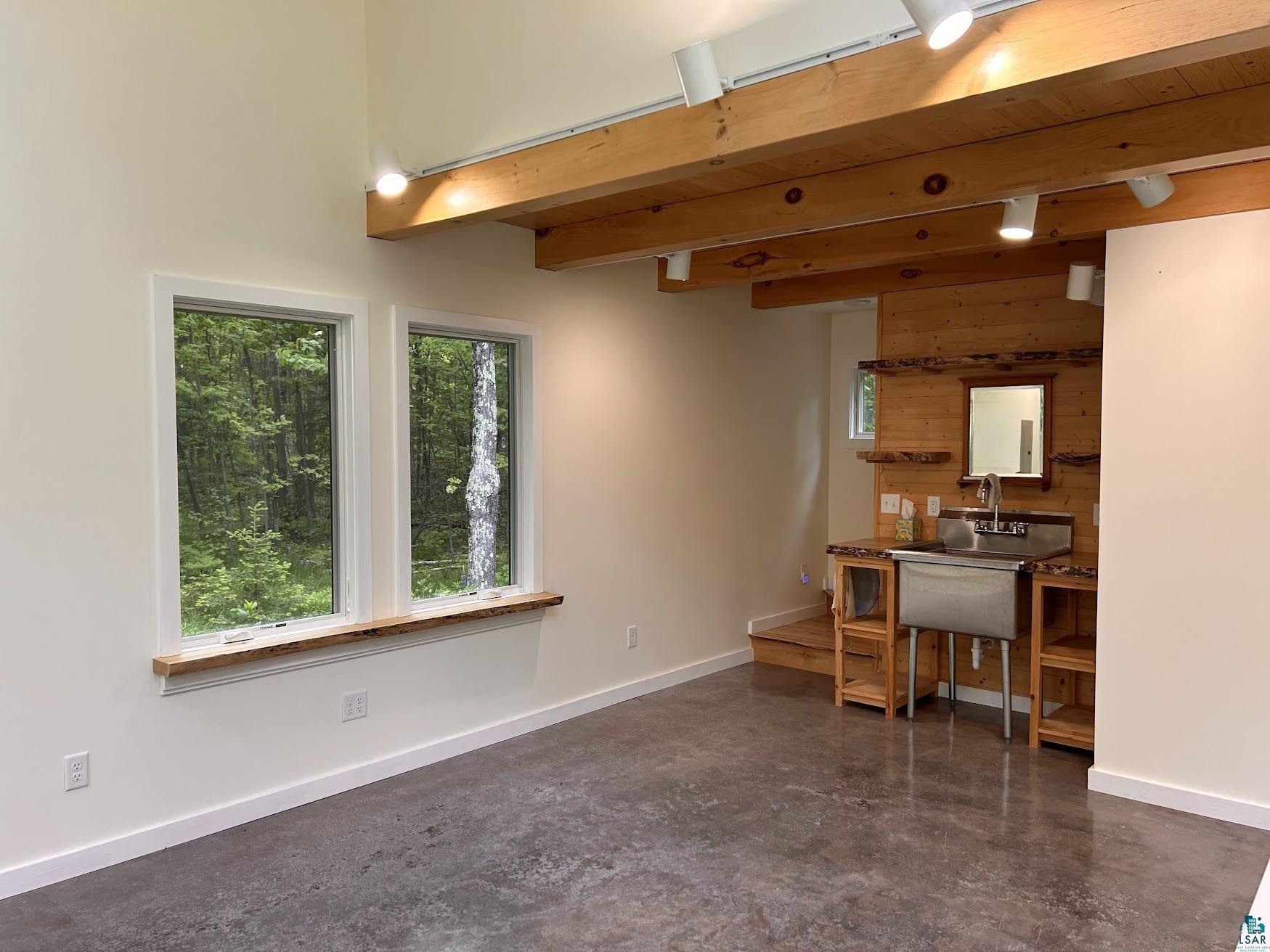 1596 North Shore Road La Pointe, WI 54850 - Photo 12 of 21 Expansive interior space featuring exposed wood beams, track lighting, and concrete flooring