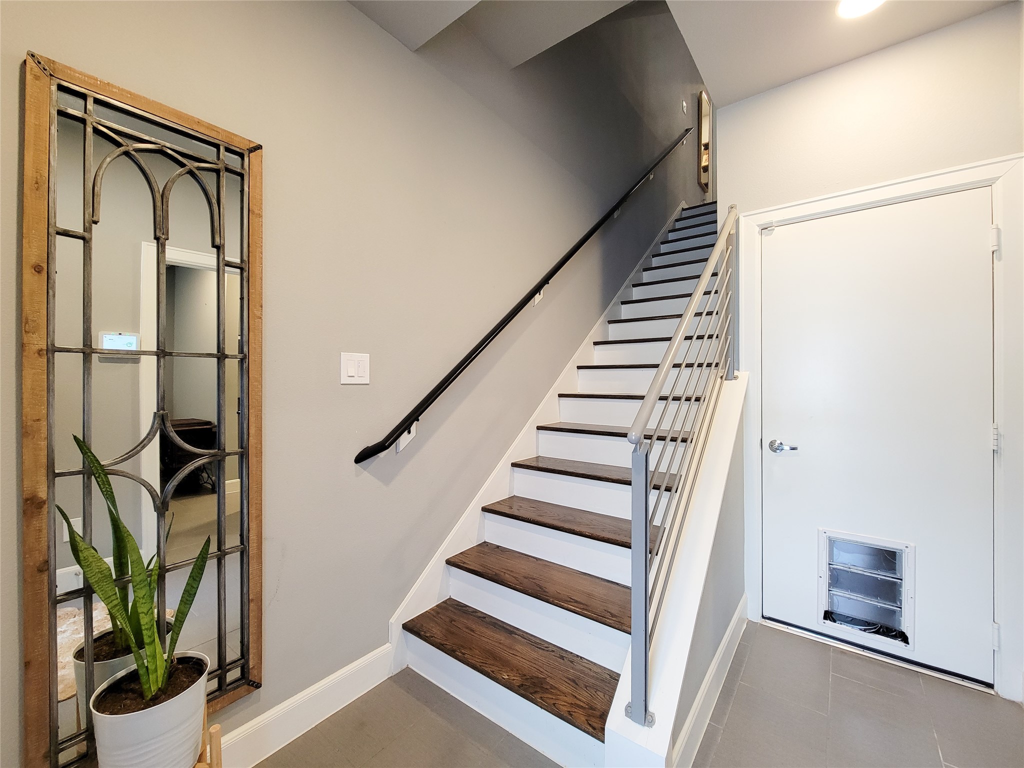1705 Eado Point Lane Houston, TX 77003 - Photo 7 of 50 Modern entryway with a staircase featuring wooden steps and a sleek metal railing. A garage door with a pet entrance adds practicality for pet owners.