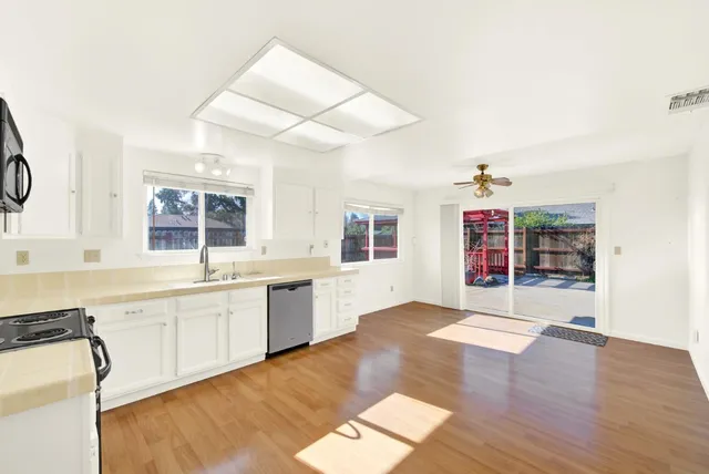 a view of a kitchen with a sink and dishwasher a stove top oven with wooden floor