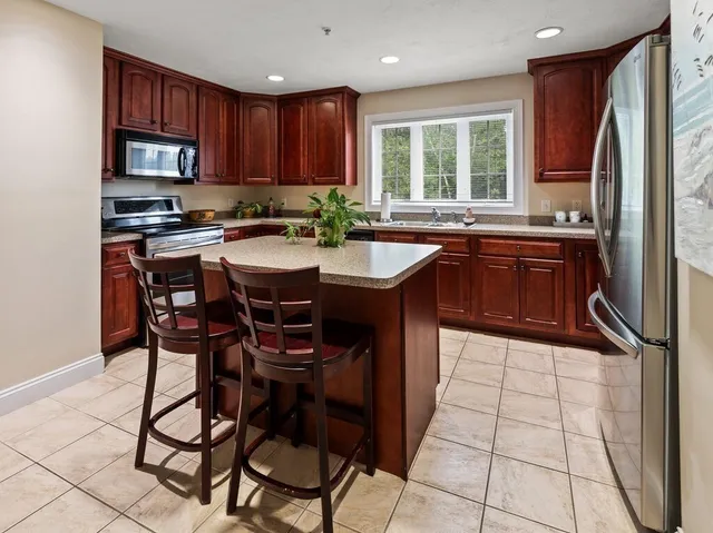 a kitchen with stainless steel appliances granite countertop a stove a sink dishwasher a microwave oven and a refrigerator with wooden cabinets