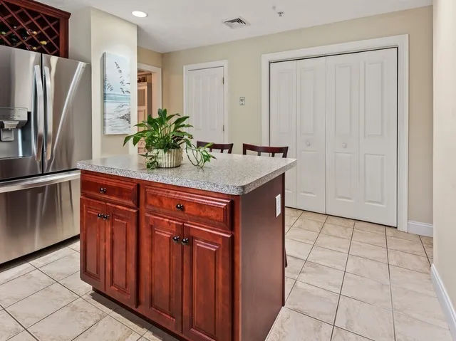 a room with stainless steel appliances granite countertop a refrigerator a sink a counter space and cabinets