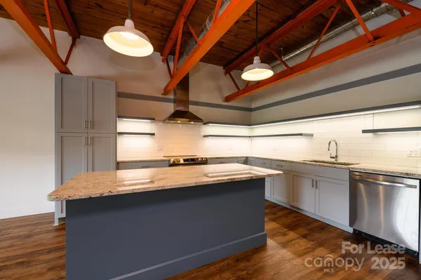 a kitchen with stainless steel appliances granite countertop a sink a stove and a wooden floors